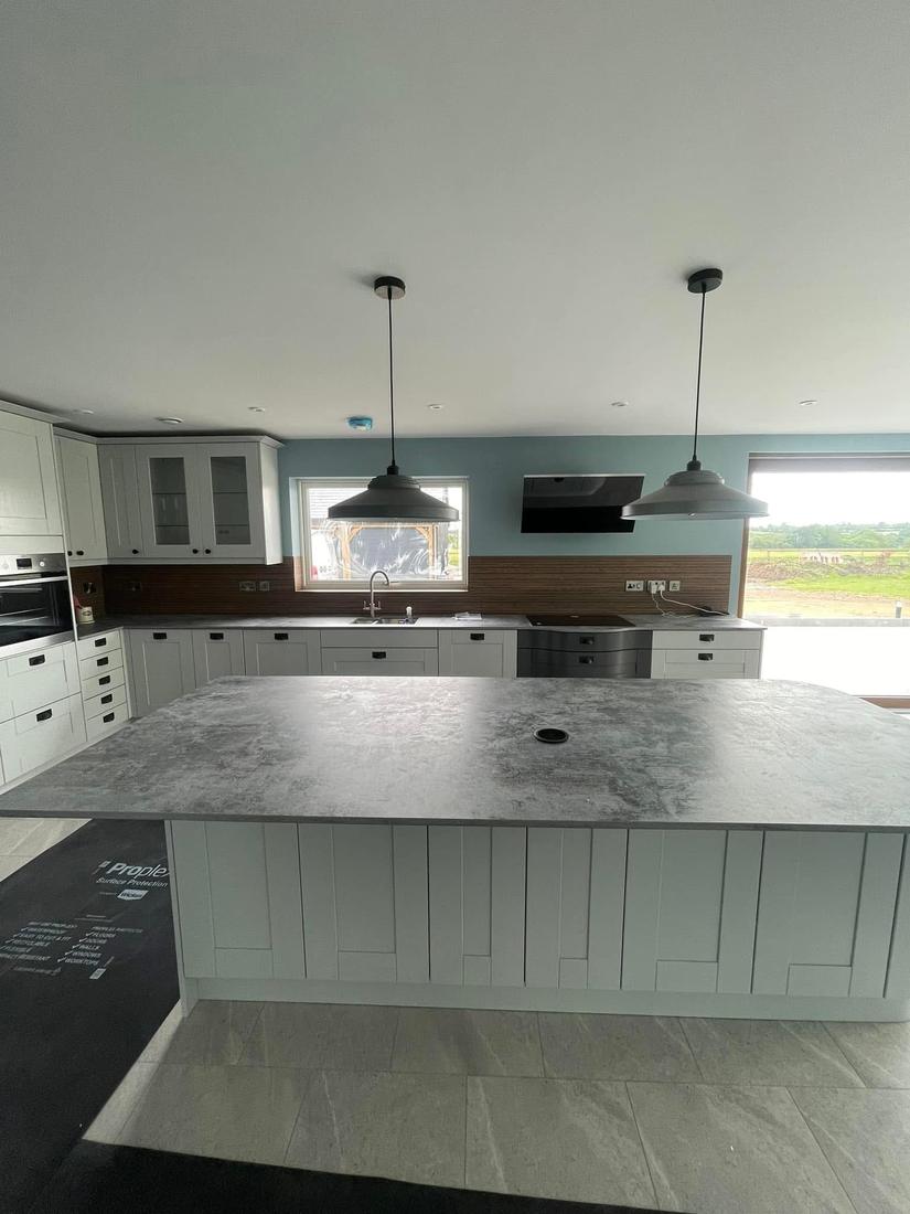 Open-plan kitchen with shaker units and curved stone island